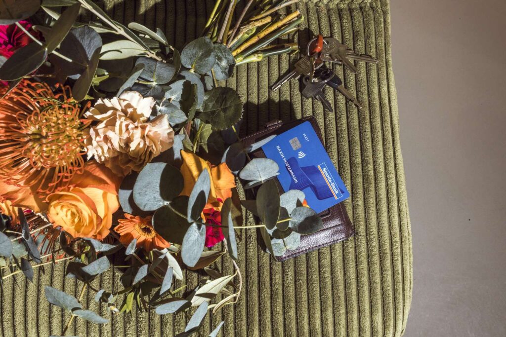 Ein bunter Blumenstrauß liegt auf einem Tisch, neben einem stehenden Staubsauger.