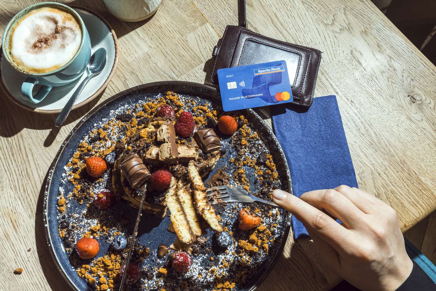 Person genießt ein reichhaltiges Fruehstueck mit Kaffee in einem Restaurant.