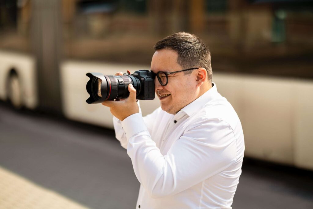 Fotograf haelt Kamera und macht Aufnahmen auf der Straße.