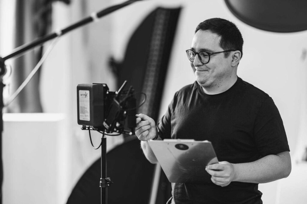Ein Fotograf im Studio mit Kameraausruestung und Beleuchtung.