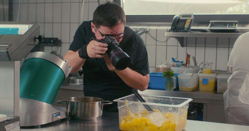 Fotograf nimmt ein Bild in einer Kueche auf mit einer Kamera.