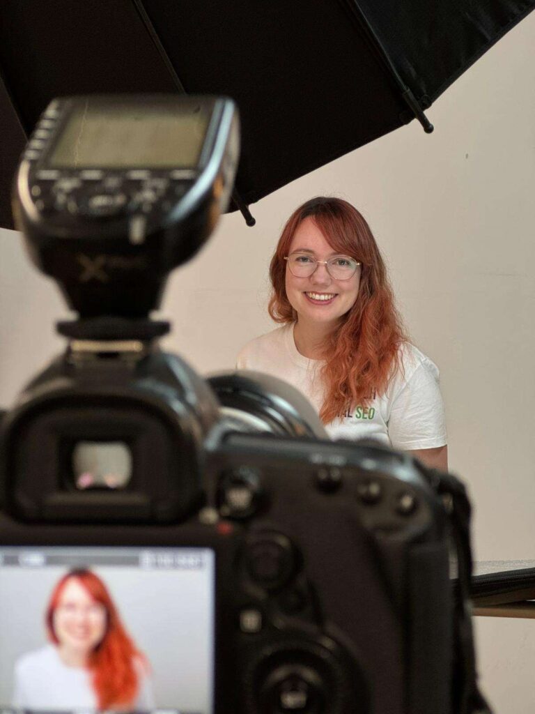 Eine Frau sitzt vor einer Kamera in einem Fotostudio.