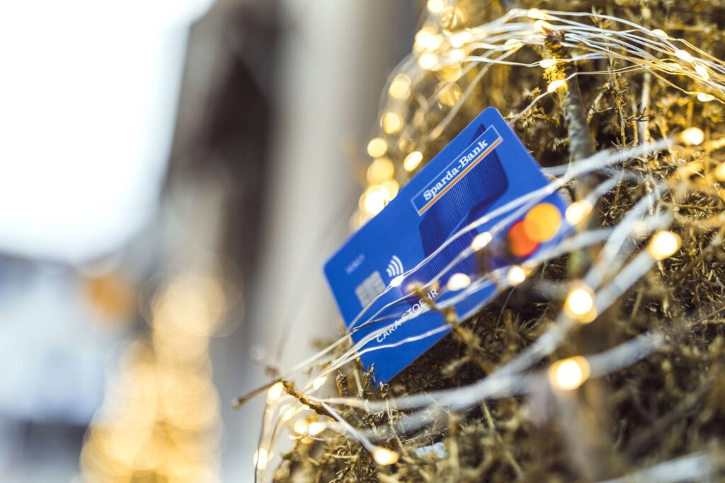 Kreditkarte zwischen Weihnachtsbeleuchtung und Dekoration.