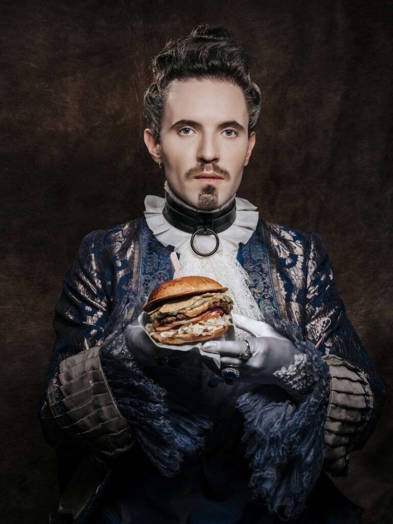 Mann in Renaissance-Kleidung haelt Burger, fotografiert von Befotomedia in Loechgau.