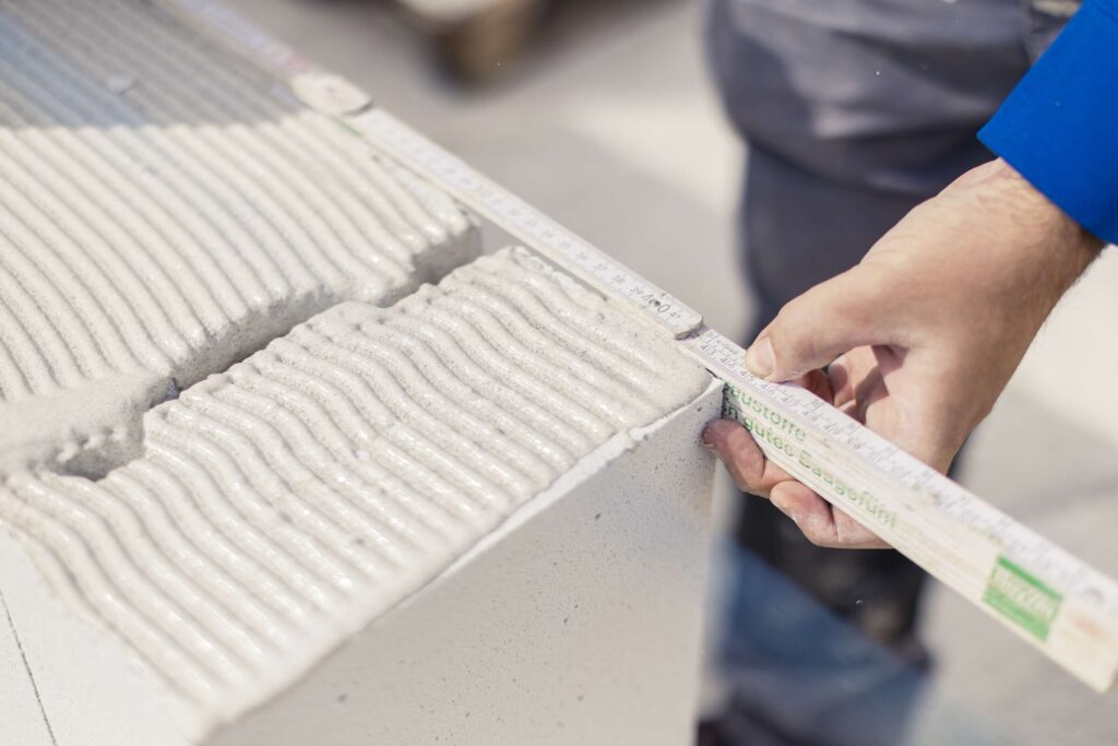 Hand misst mit einem Meterstab nach.