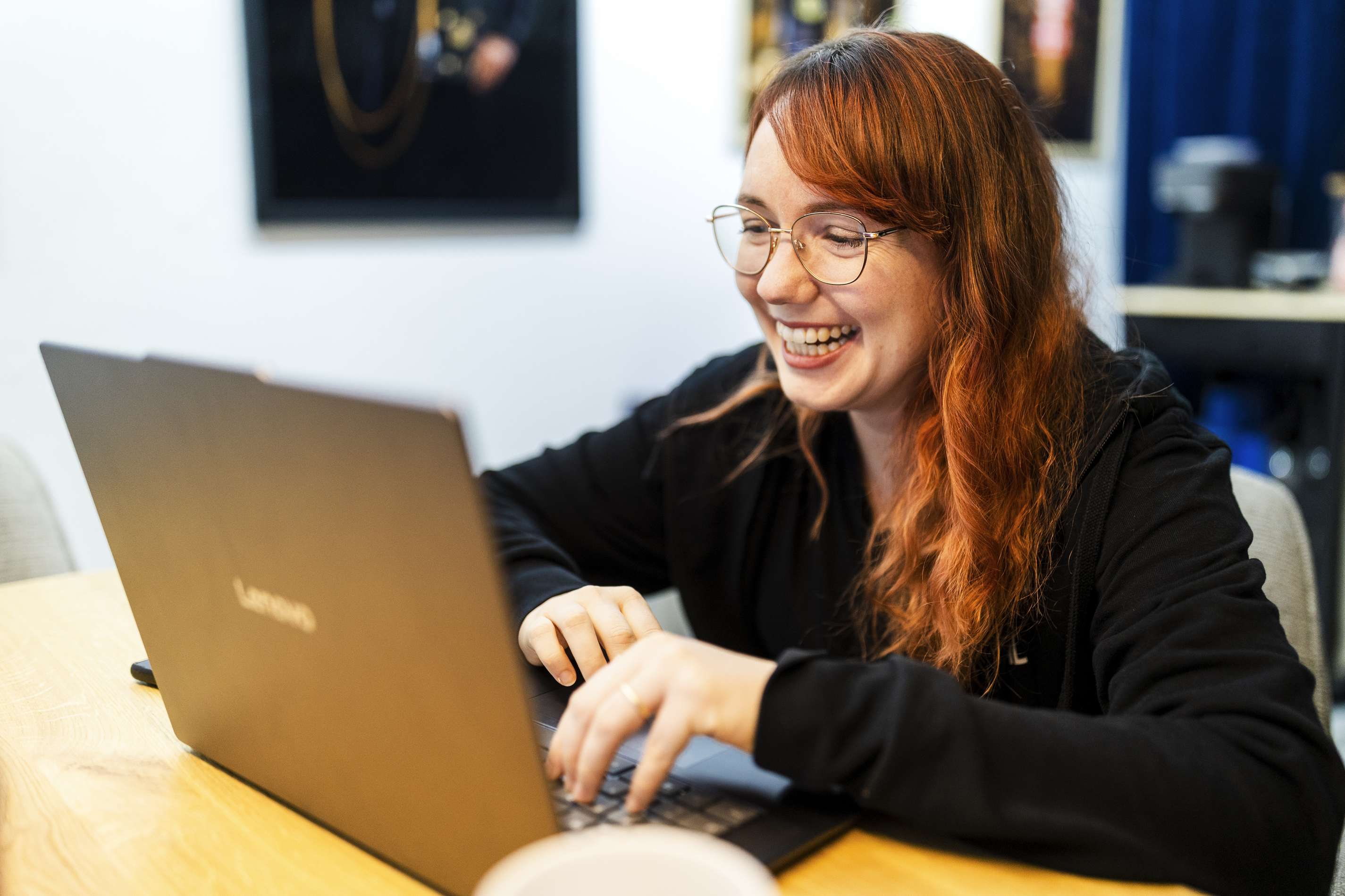 Junge Frau arbeitet laechelnd an einem Laptop im Buero.