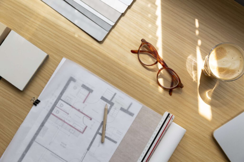 Architekturplaene und Brille auf einem Schreibtisch bei Tageslicht