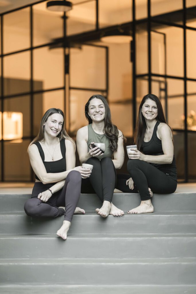 Drei Frauen in sportlicher Kleidung sitzen auf einer Treppe.