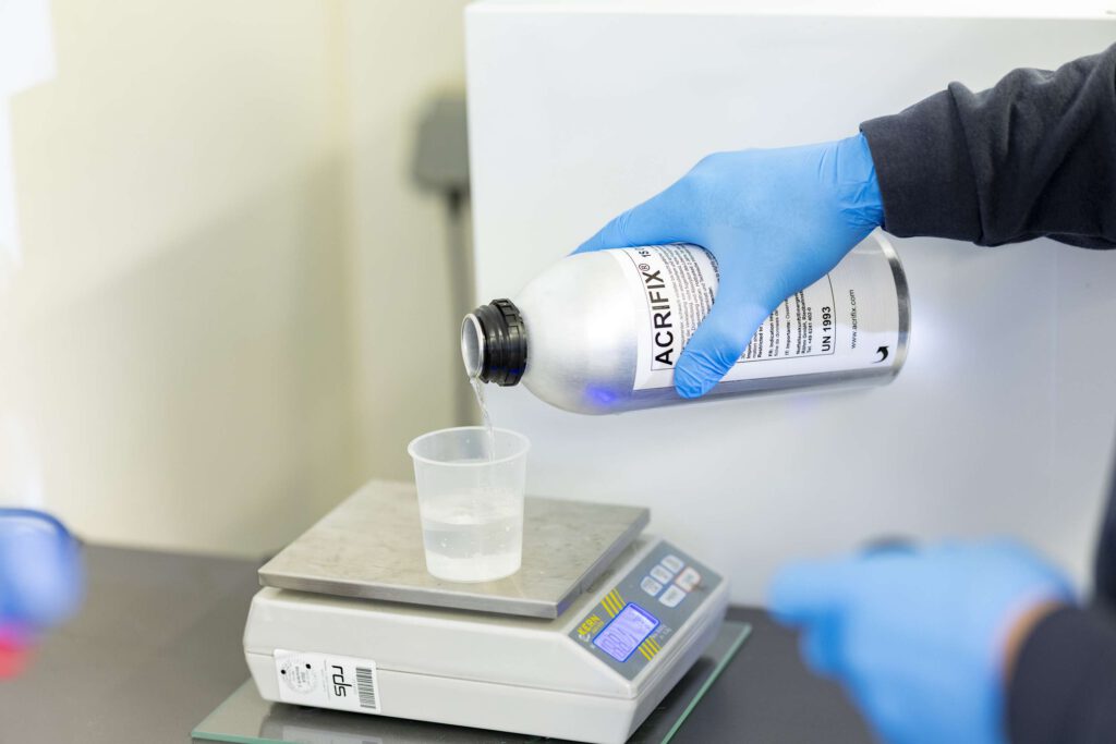 Ein Mitarbeiter wiegt Chemikalien auf einer Waage bei Ebert Kunststoffbearbeitung.