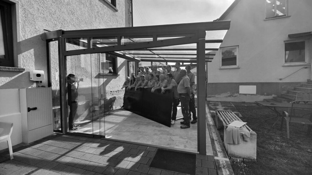 Eine ueberdachte Eingangsbereich mit mehreren Personen im Hintergrund.