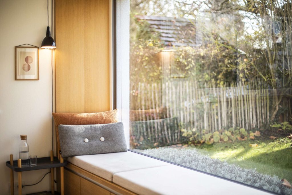 Gemuetlicher Leseplatz auf einer Fensterbank mit Blick in den Garten.