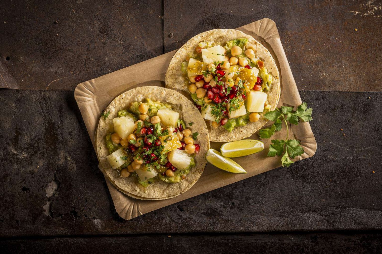 Zwei Tacos mit frischen Zutaten auf einem Holzbrett serviert.