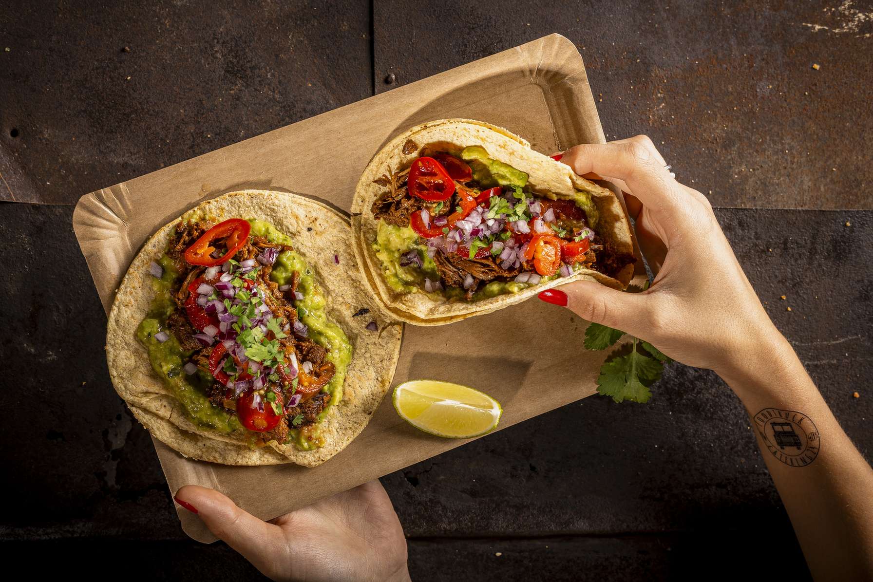 Zwei koestliche Tacos von Foodtruck Catering24 auf einem Tablett serviert.