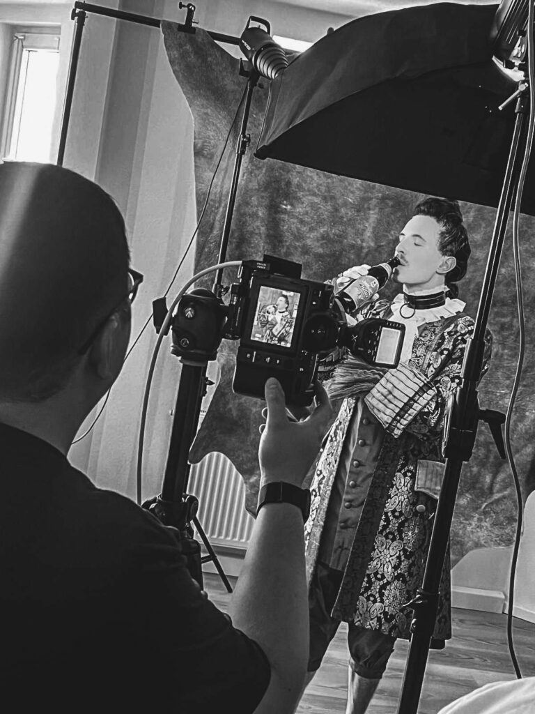 Ein Fotograf macht ein Portraetfoto einer Person in traditioneller Kleidung im Studio.