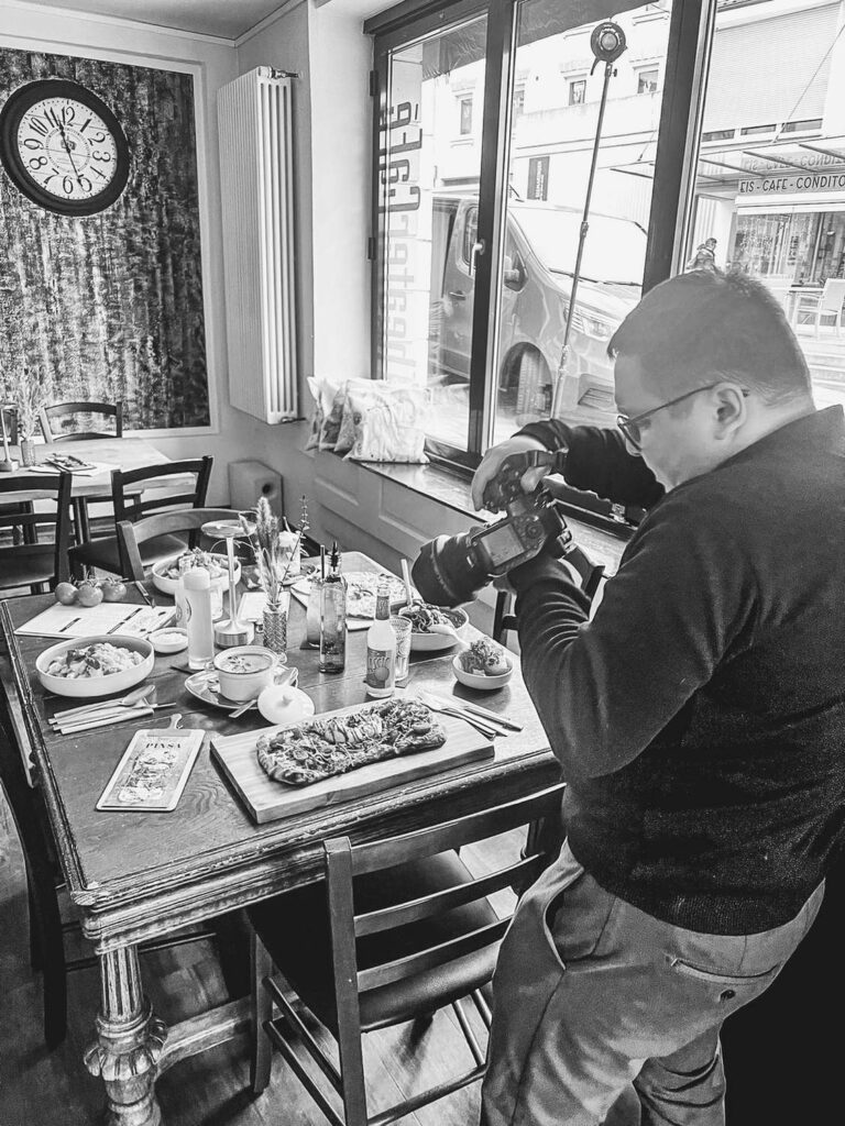 Ein Fotograf macht Bilder von einem gedeckten Tisch in einem Restaurant.