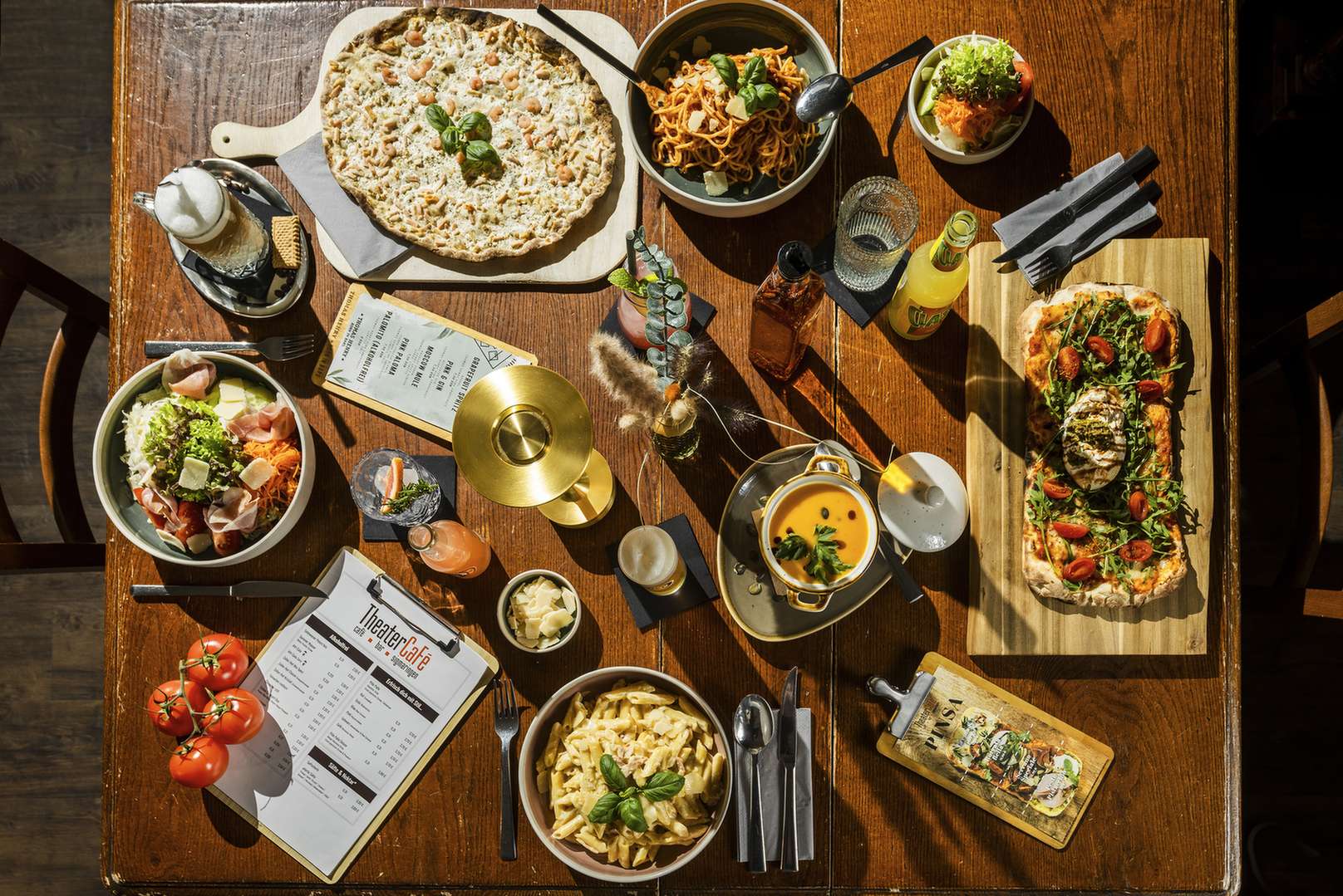 Ein gedeckter Holztisch mit verschiedenen italienischen Gerichten und Getraenken.