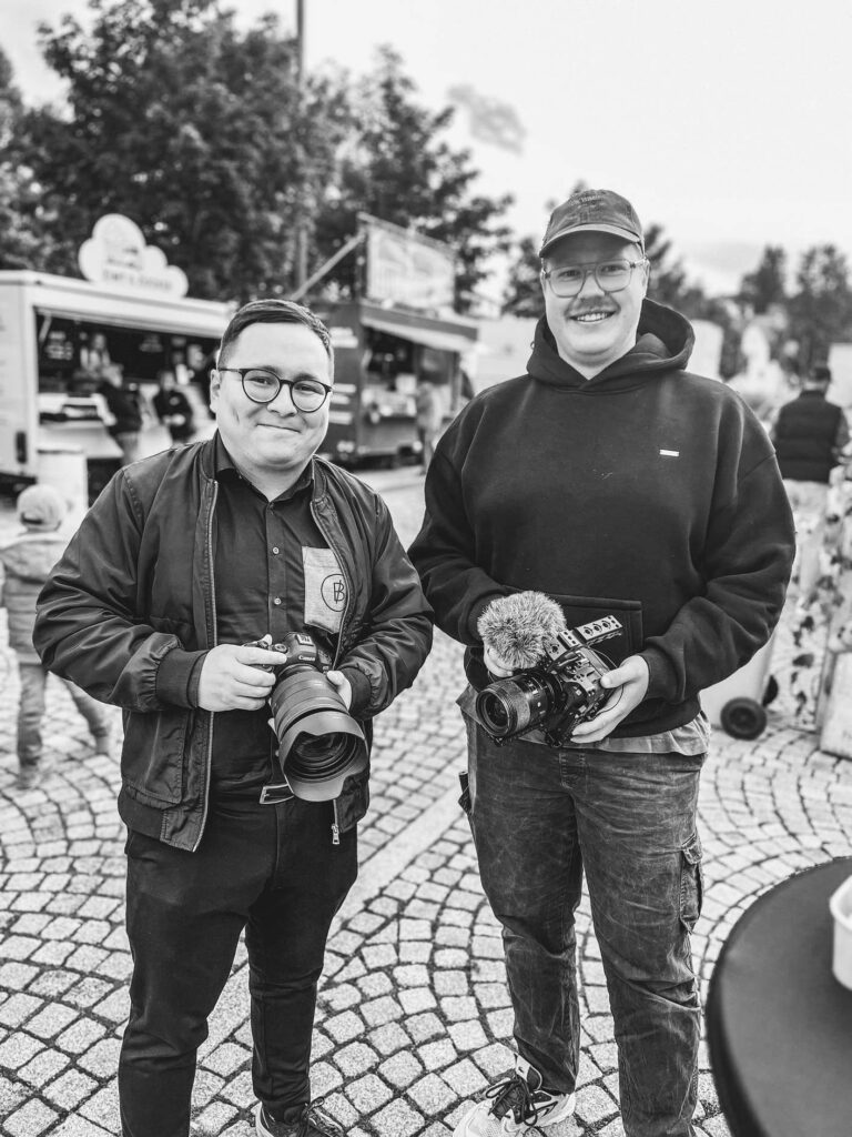 Zwei Personen auf einem Flohmarkt mit Kameras.