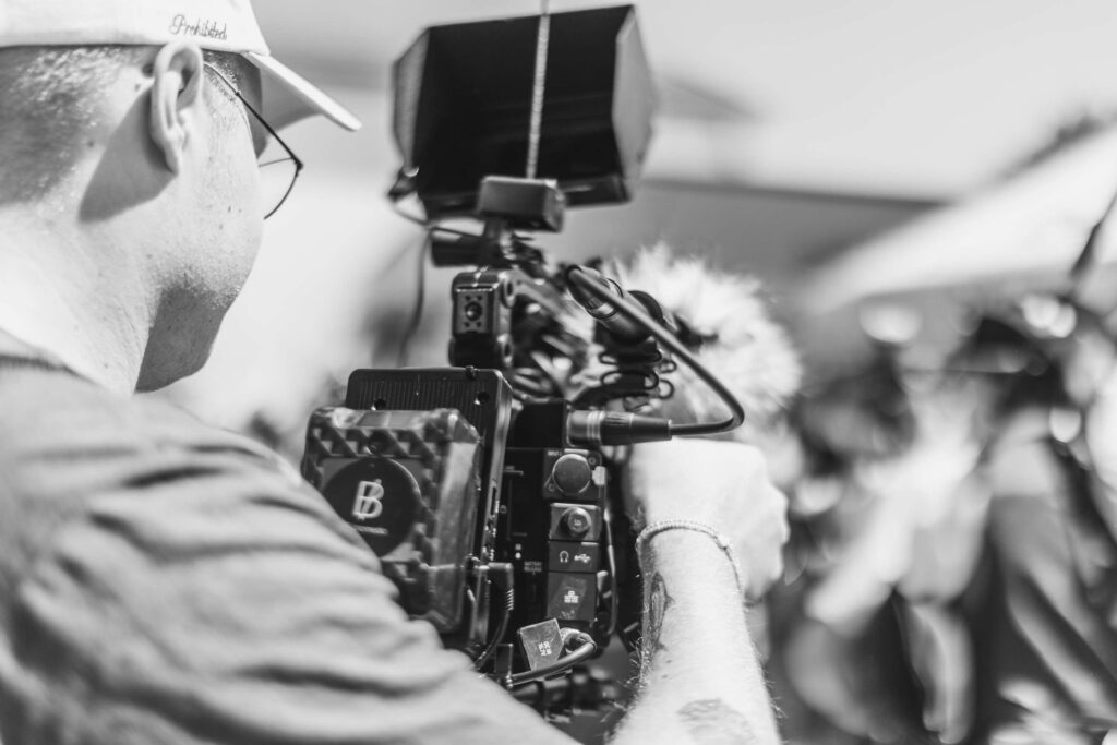 Schwarz-Weiß-Foto eines Kameramanns, der ein professionelles Filmset bedient