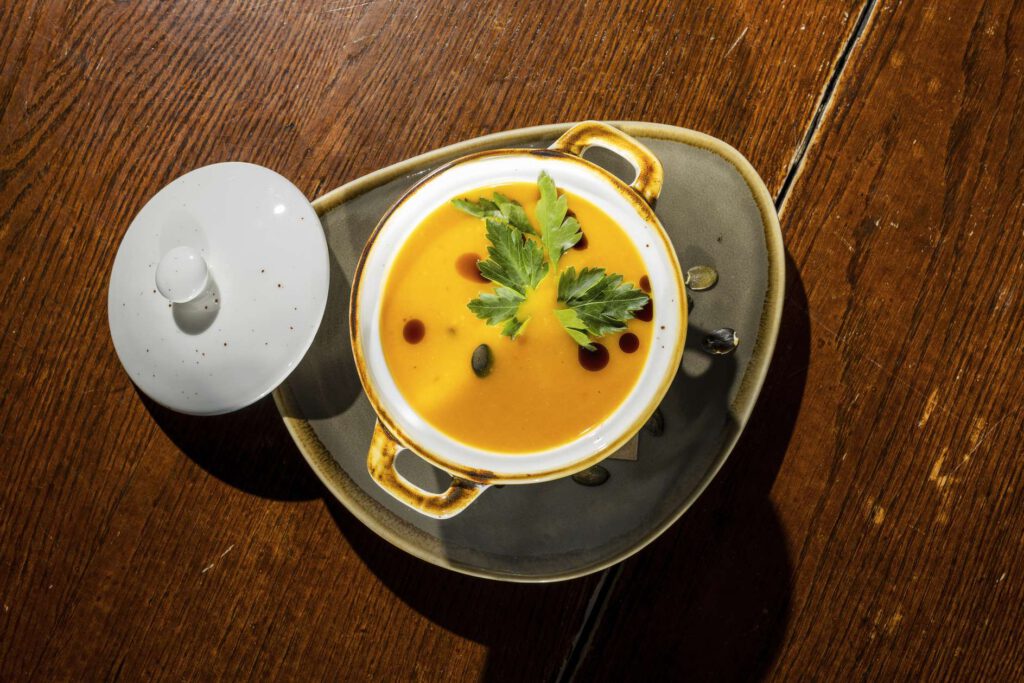 Kuerbissuppe mit Kernen in einer Schuessel auf einem Tisch.