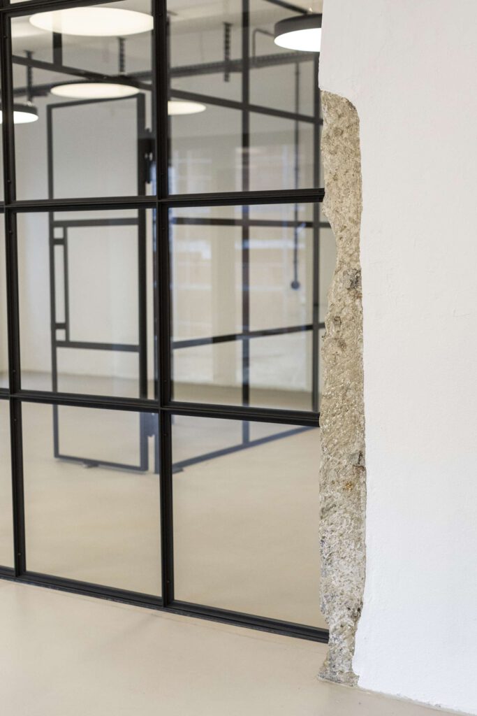 Moderner Bueroraum mit Glaswaenden und freiliegendem Mauerwerk.