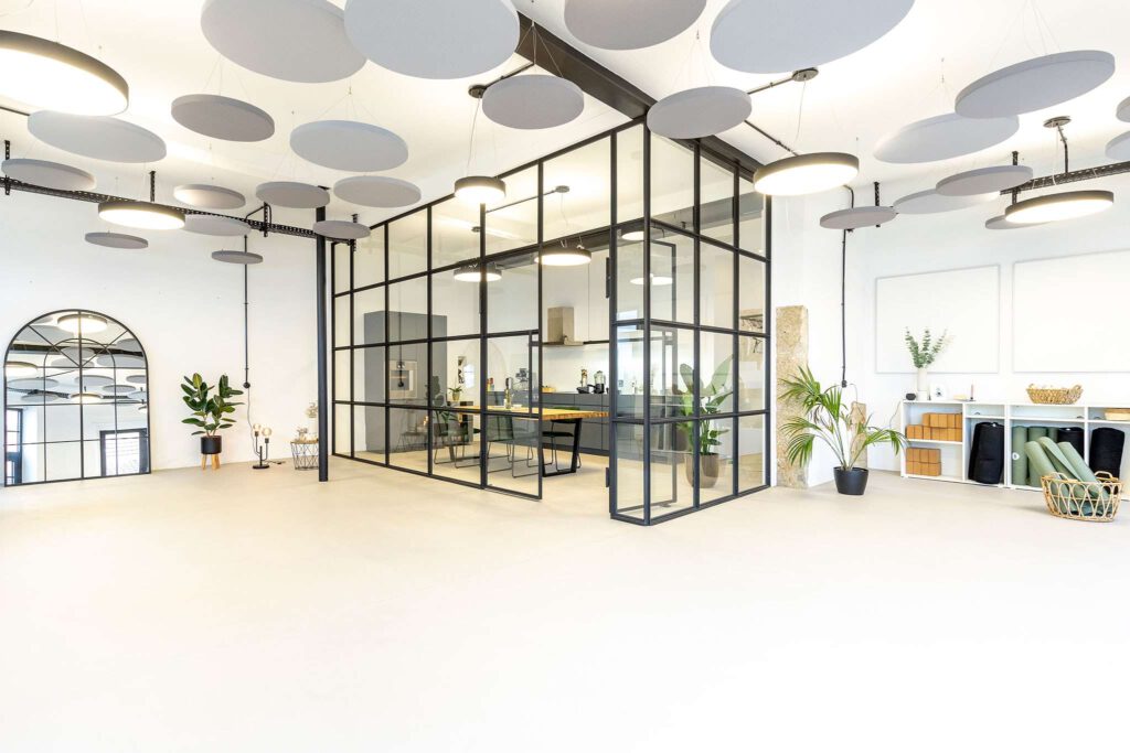 Moderner Bueroinnenraum mit Glastrennwand und Pflanzen.