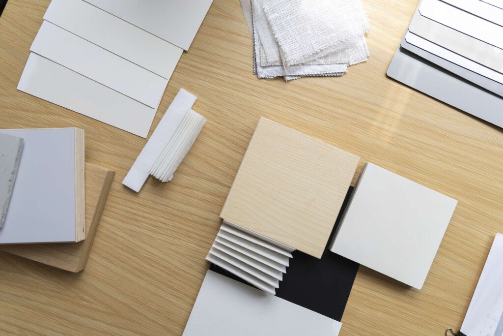 Schreibtisch mit verschiedenen Notizbuechern und Kartons in neutralen Toenen.