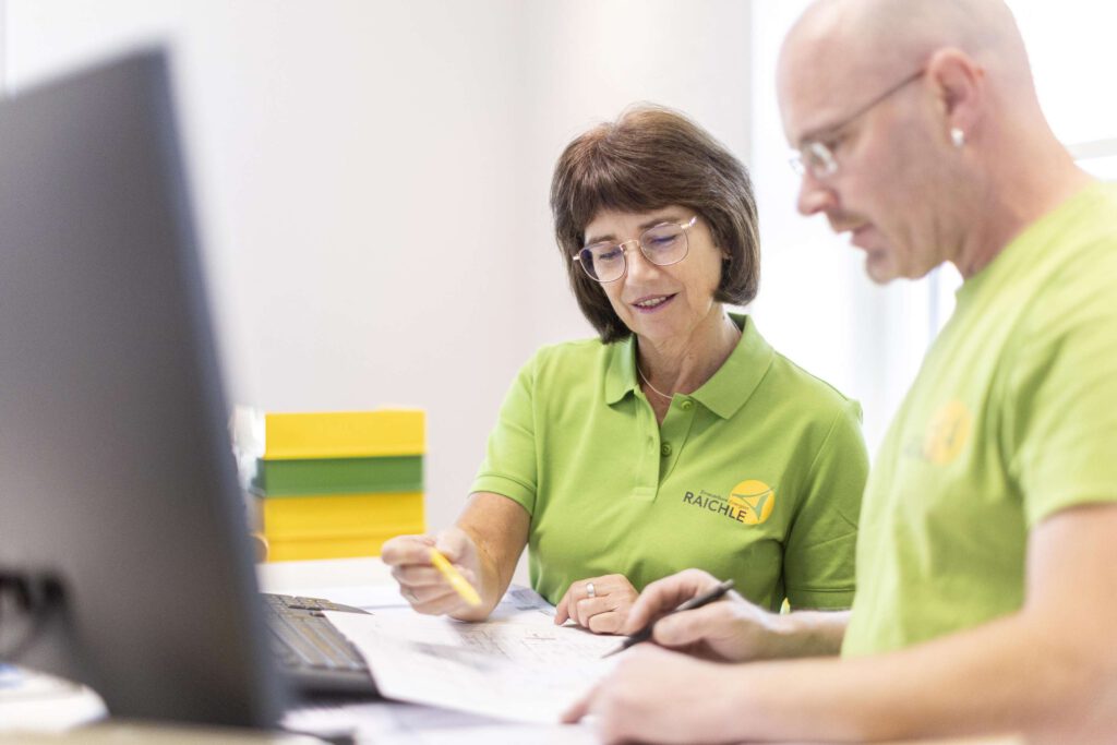 Zwei Personen bei der Besprechung eines Projektdokuments am Computer.