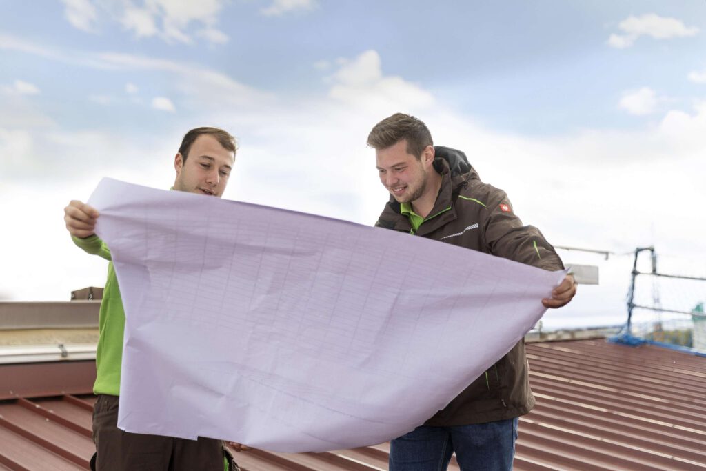 Zwei Mitarbeiter von Raichle GmbH bei der Planung auf einem Dach.