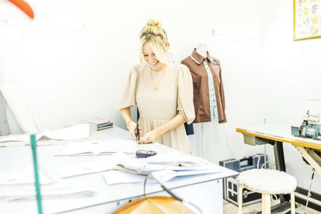 Eine Schneiderin arbeitet in einer hellen Werkstatt an einem Schnittmuster.