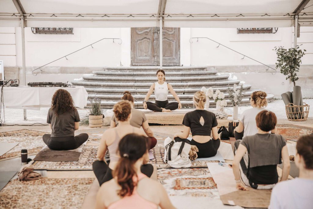 Gruppe von Menschen meditiert in einem Yogakurs in einem offenen Raum