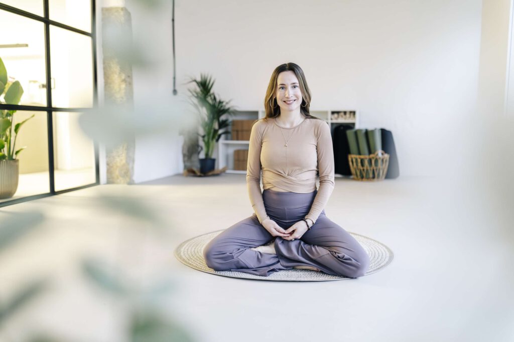 Eine Person meditiert in einem hellen Yoga-Studio.