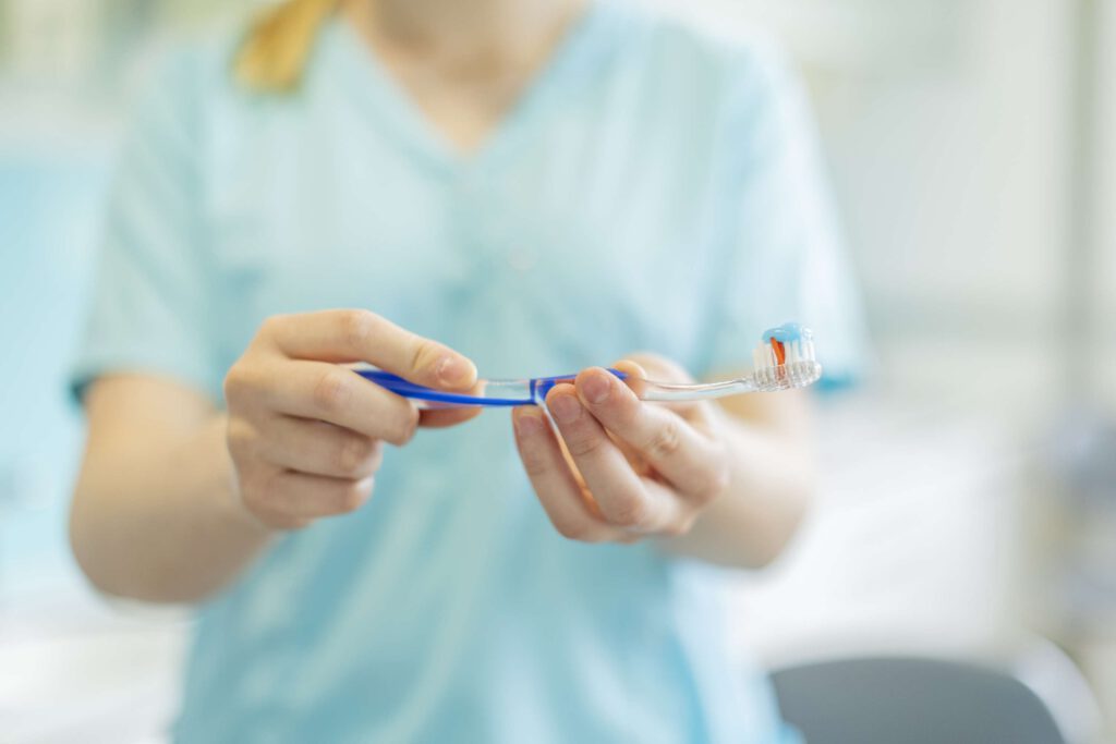 Mitarbeiter in blauer Kleidung haelt zahnmedizinische Instrumente in der Zahnarztpraxis Stegherr & Stegherr in Albstadt.
